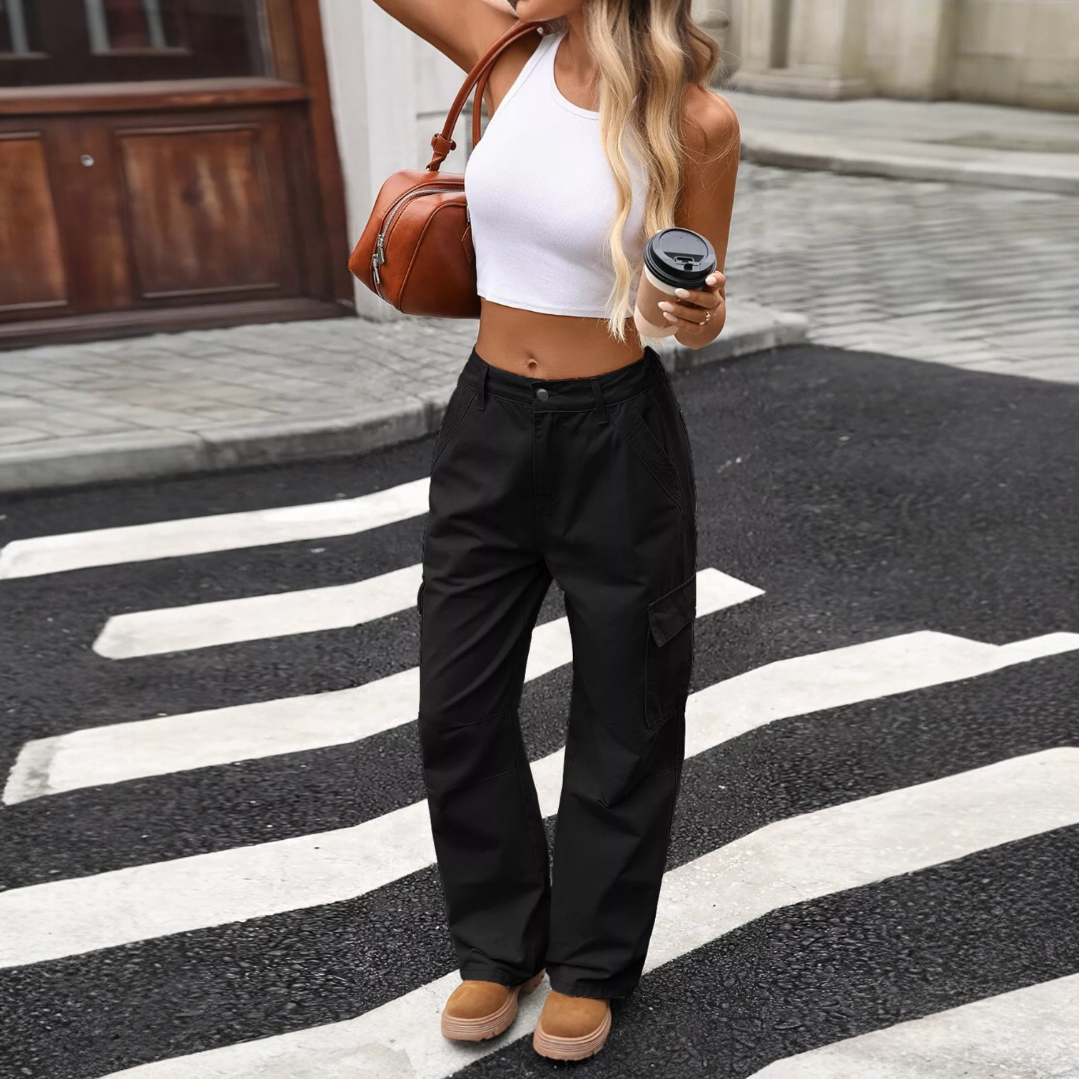Black cargo pants with side pockets, worn by a model in an urban setting, holding a coffee cup.