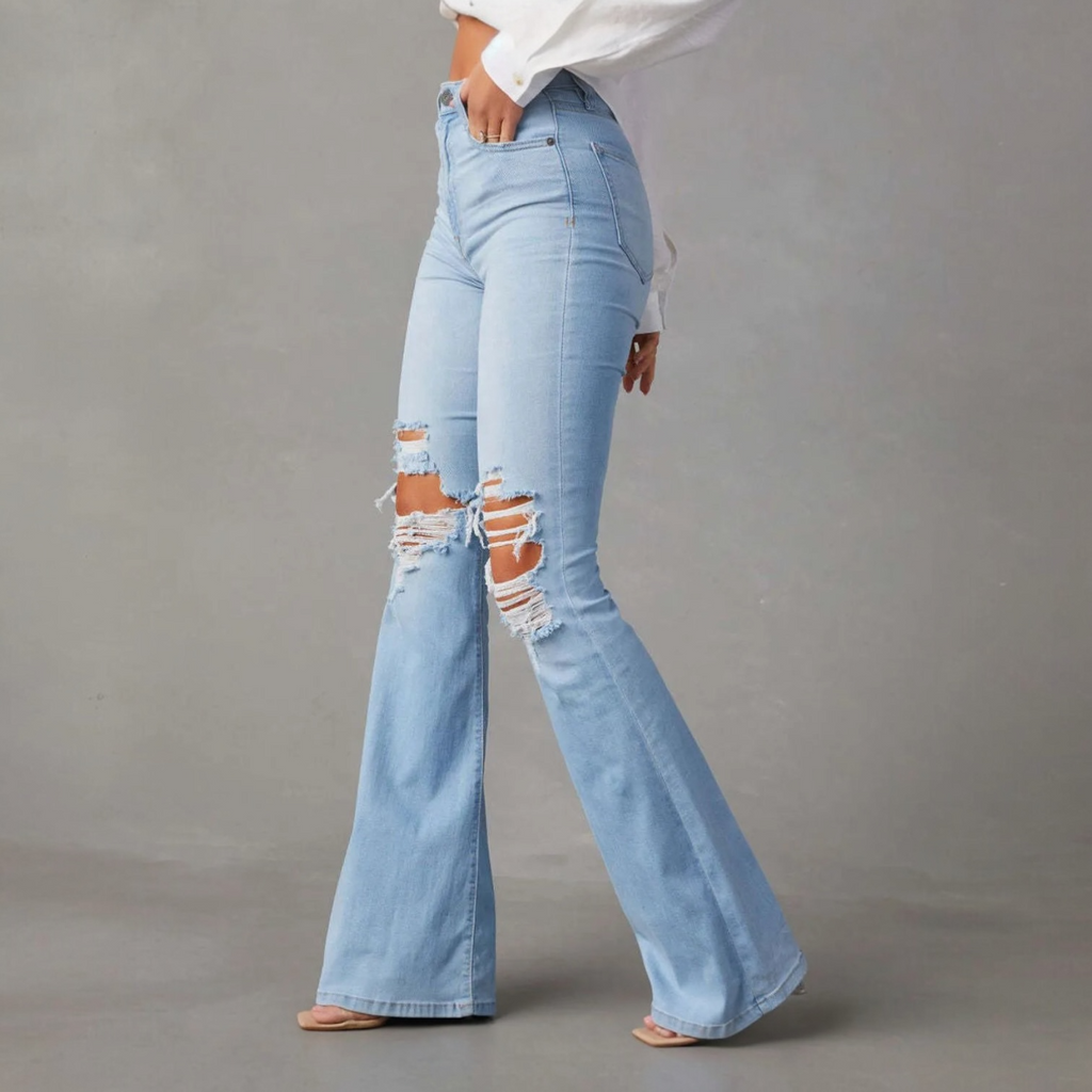 Light wash distressed flare jeans with rips at the knees, perfect for bold fashion choices.