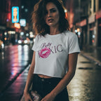 Cropped white baby tee with bold 'Pretty Toxic' graphic and lip print, worn by a model in an urban nighttime setting.