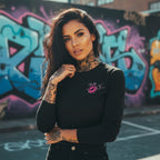 Black long sleeve shirt with front graphics, worn by a model against a graffiti backdrop. Perfect for bold lassies!