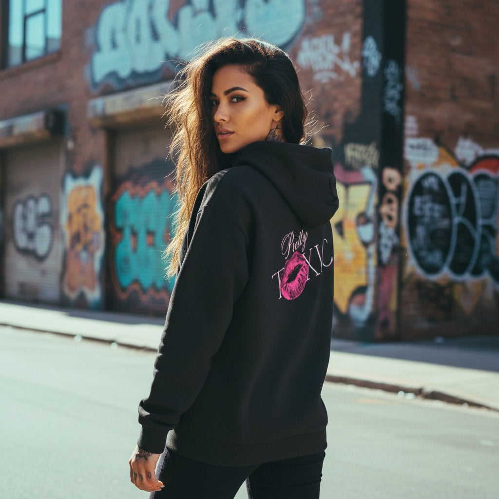 Black oversized hoodie with embroidered logo and bold graphic, worn by a model in an urban setting.