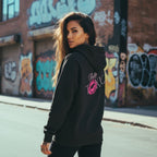 Black oversized hoodie with embroidered logo and bold graphic, worn by a model in an urban setting.
