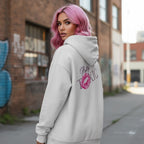 Light-colored oversized hoodie with 'Pretty Toxic' graphic and kiss mark, worn by a model with pink hair in an urban setting.