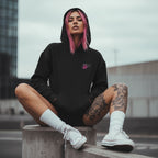 Black oversized hoodie with embroidered logo, model sportin' it in an urban setting with white high-top sneakers.