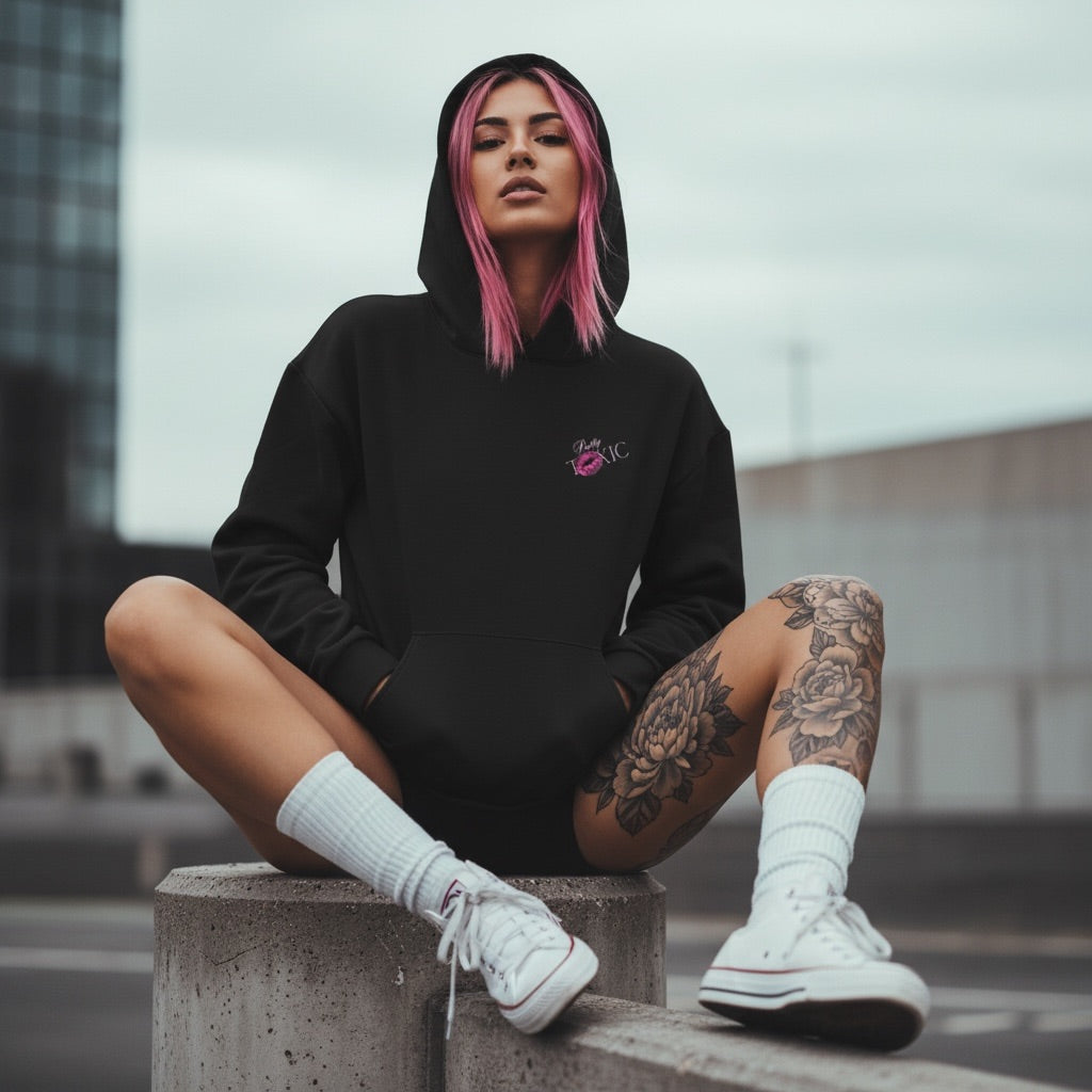 Black oversized hoodie with embroidered logo, model sportin' it in an urban setting with white high-top sneakers.